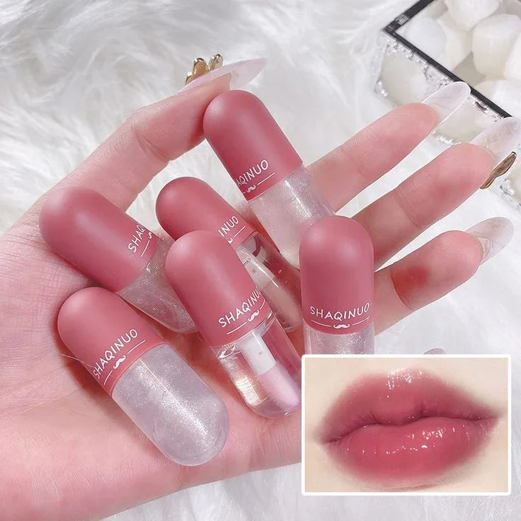 Brillo labial en cápsula transparente, hidratante y efecto cambiante de color, muestra labios brillantes.