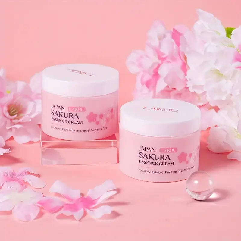 Cremas esencia Sakura japonesas para cuidado facial sobre fondo rosa con flores decorativas.