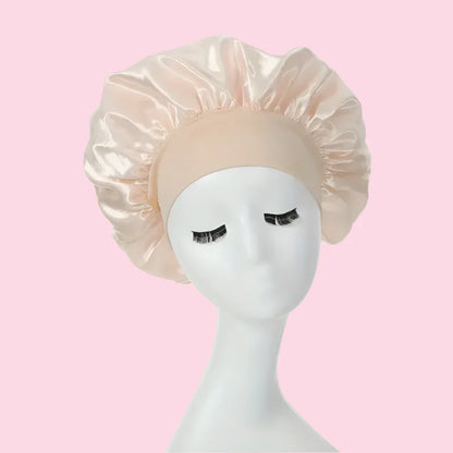 Gorro de satén beige para el cabello sobre maniquí blanco fondo rosa, cuidado capilar coreano.