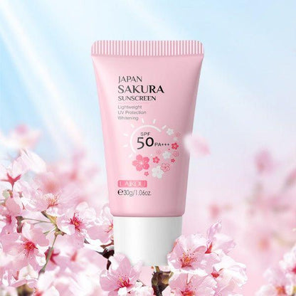 Protector solar japonés Sakura SPF 50 en envase rosa, rodeado de flores de cerezo.