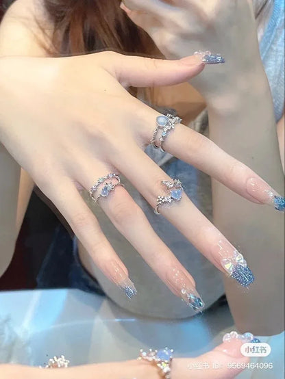 Manos con manicura coreana de uñas largas decoradas y anillos plateados elegantes