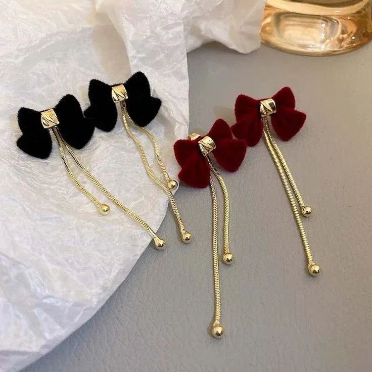 Aretes de lazo negro y rojo con cadenas doradas, estilo coreano sobre fondo neutro
