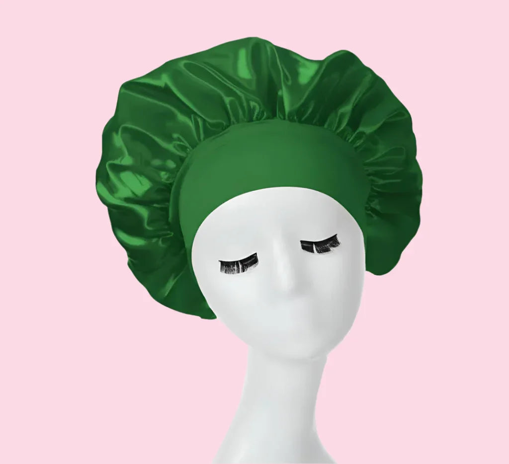 Gorro de satén verde para cabello, exhibido en maniquí blanco sobre fondo rosa, cuidado capilar.